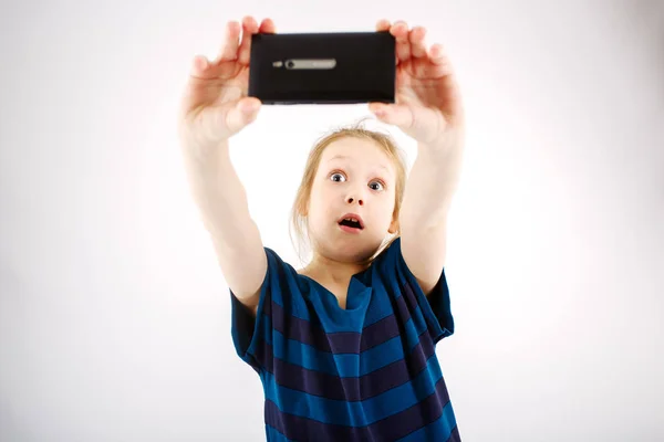 A little girl shoots on a smartphone shocking her video — Stock Photo, Image