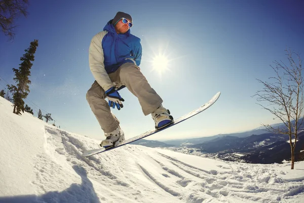 Snowboarder pulando do trampolim contra o céu — Fotografia de Stock