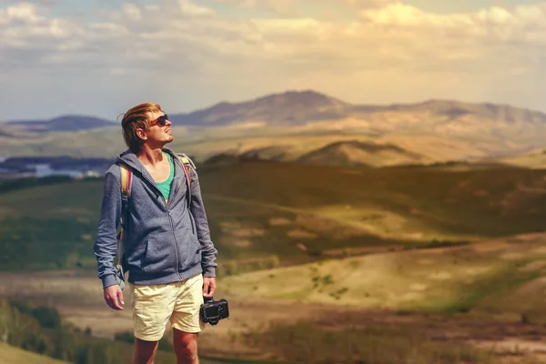 A young man with a camera in the mountains. — Stock Photo, Image