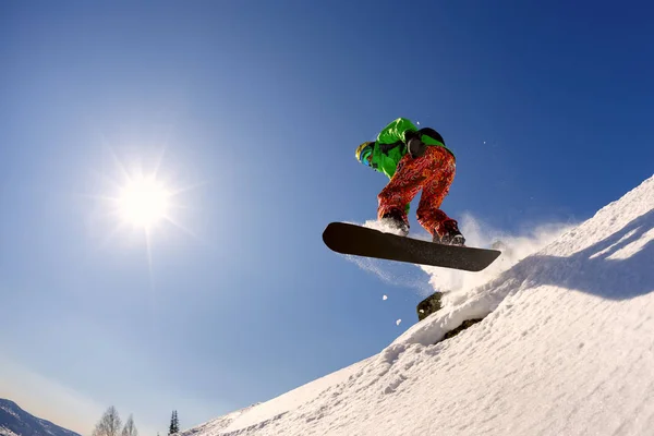 Snowboardzista skoki z trampoliny przeciw błękitne niebo — Zdjęcie stockowe