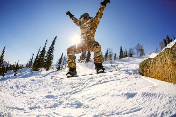 Der Snowboarder springt vom Sprungbrett gegen den blauen Himmel — Stockfoto