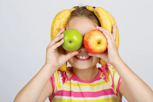 Ragazzina allegra con mele, limone e banana pone positiviv — Foto Stock