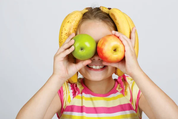 Niña alegre con manzanas, limón y plátano posa positiv —  Fotos de Stock