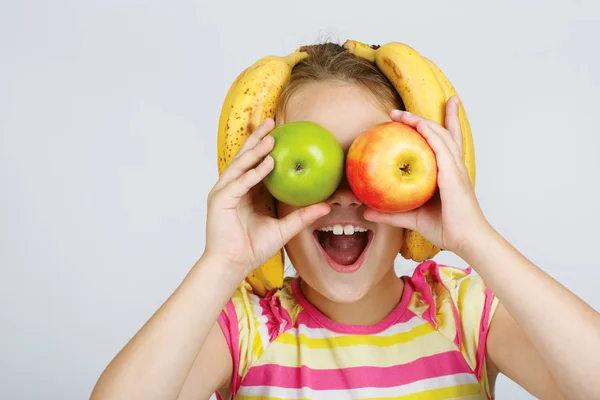 Niña alegre con manzanas, limón y plátano posa positiv —  Fotos de Stock