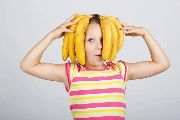Pequeña niña alegre juega con un peinado de plátano —  Fotos de Stock