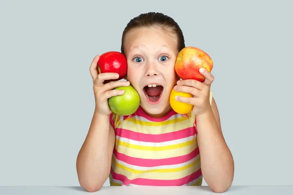Veselá holčička s jablky a citronem představuje pozitivně v s — Stock fotografie