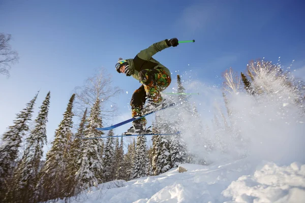 De skiër springt uit een springplank in het skigebied. — Stockfoto