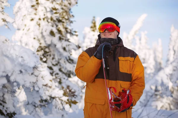 Seorang pria muda adalah snowboarder dengan papan seluncurnya di atas sebuah moun — Stok Foto