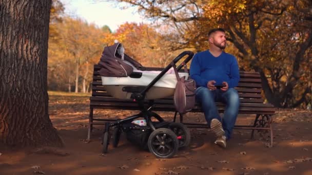 Giovane papà è seduto nel parco con un bambino — Video Stock