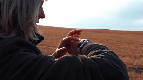 Το νεαρό κορίτσι χρησιμοποιεί ένα έξυπνο ρολόι στα βουνά. — Αρχείο Βίντεο