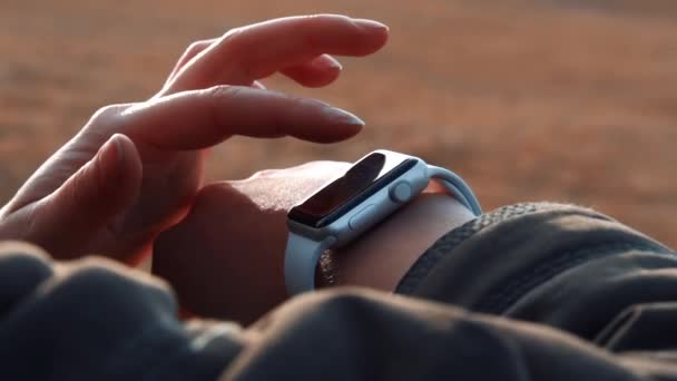 Jovem usa um relógio inteligente nas montanhas na natureza — Vídeo de Stock