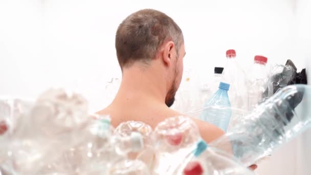 Homem senta-se com as costas em uma pilha de plástico — Vídeo de Stock