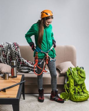 beautiful climber with climbing equipment at home clipart
