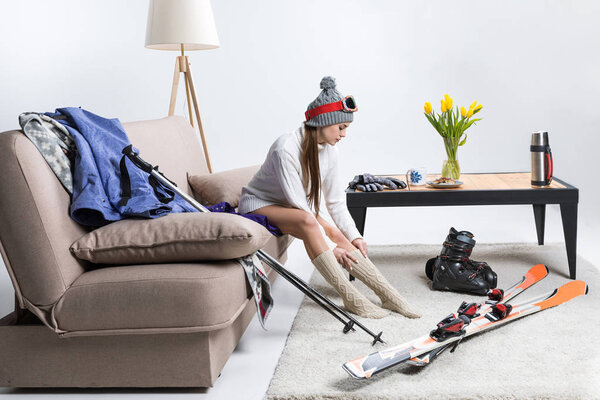 young sportswoman wearing warm socks, ski equipment lying on floor