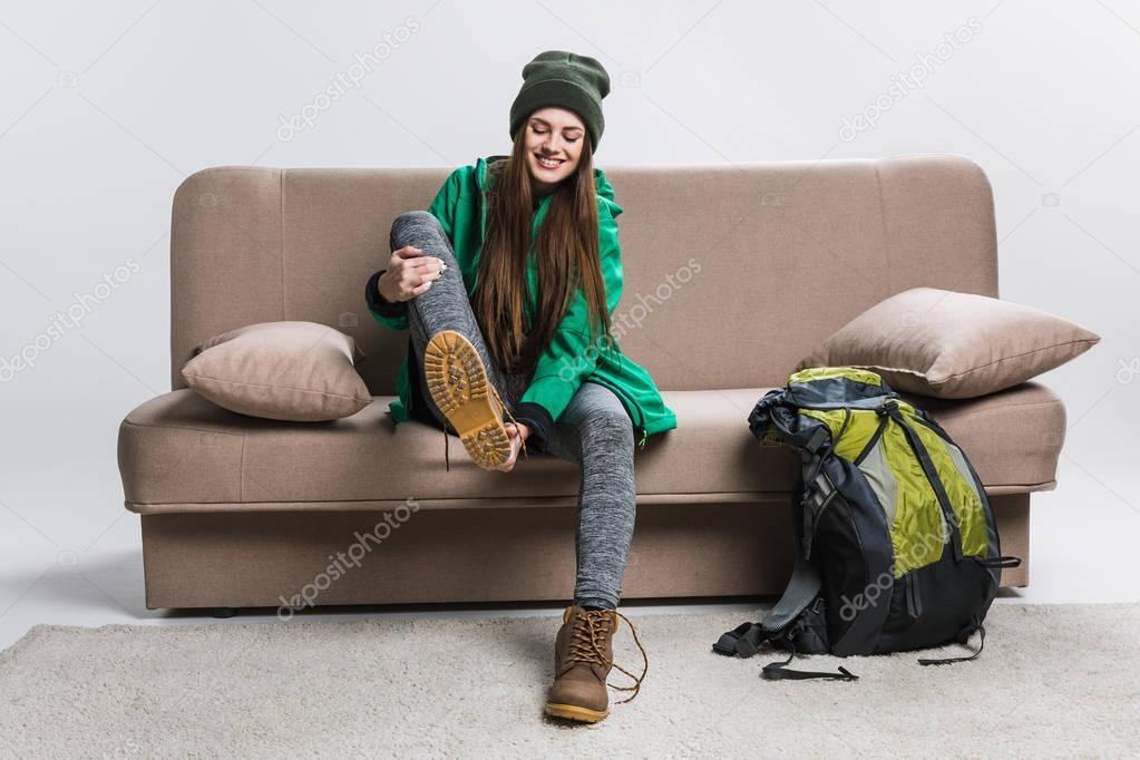 happy girl wearing hiking boots on sofa with backpack