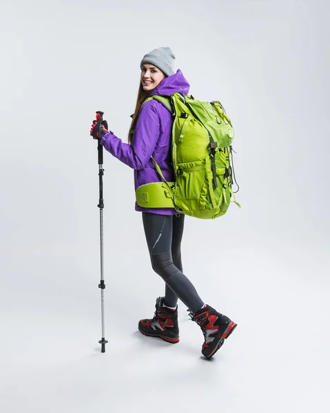 Wanderin in warmer Kleidung mit Rucksack und Wanderausrüstung, isoliert auf grau — Stockfoto