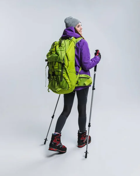 Schöner Wanderer mit Rucksack und Wanderstöcken, isoliert auf grau — Stockfoto