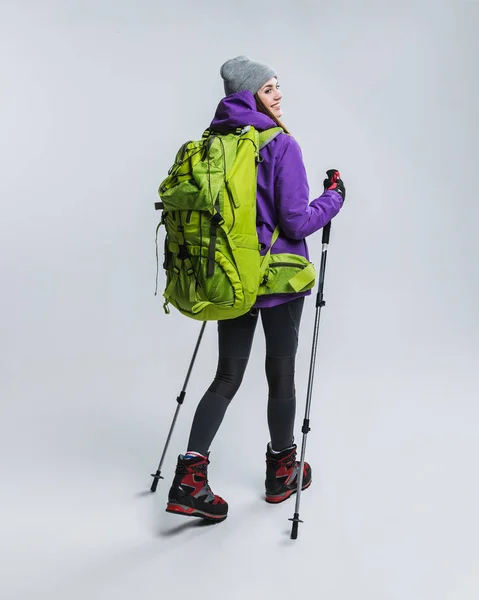 Bellissimo escursionista con zaino e bastoni da trekking, isolato su grigio — Foto stock