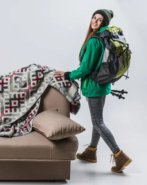 Schöne Wanderin mit Rucksack am Sofa mit Karo — Stockfoto