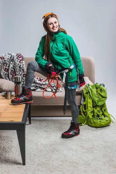 Schöne lächelnde Bergsteigerin im Helm mit Kletterausrüstung zu Hause — Stockfoto