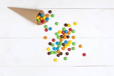 Renkli çikolata hapları Beyaz ahşap arka plan üstünde şekerleme 