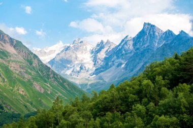 Orman ve dağ yamaçları dağ, dağ zirveleri, bulutlar ve mavi gökyüzü arka planı. Narzan Vadisi, Kuzey Kafkasya, Kabardey-çatışmalar işgalciler