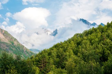 Arka plan dağlar ve Dağ doruklarına karşı orman ve dağ yamaçları bulutlar ve mavi gökyüzü ile kaplı. Narzan Vadisi, Kuzey Kafkasya, Kabardey-çatışmalar işgalciler