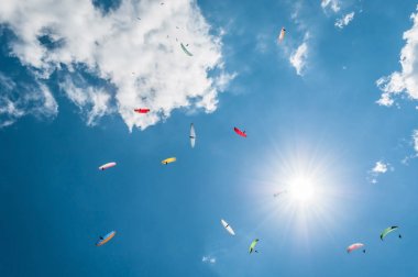 Güneşin ve bulutların arka planı mavi gökyüzünde paraşütler oraya. Alt görünümü
