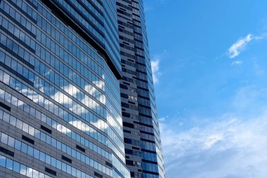 Reflections of sky and clouds in the windows of a modern business building. Low angle view against a blue sky. Business District Moscow City.