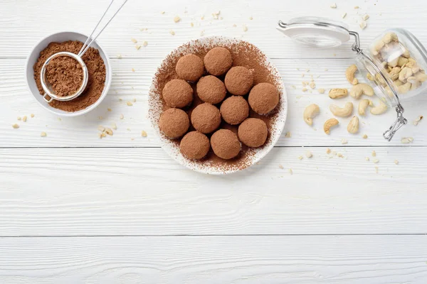 Vegan food energy balls with dates, keshtyu and cocoa. Raw diet. Good nutrition. Minimalism concept. White wood background. Copyspace from below. Flat lay.