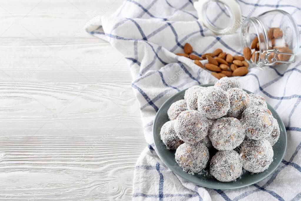 Homemade energy balls with prunes, almond and coconut. Vegan food. Raw diet. Good nutrition concept. White wood background. Copyspace on the left.