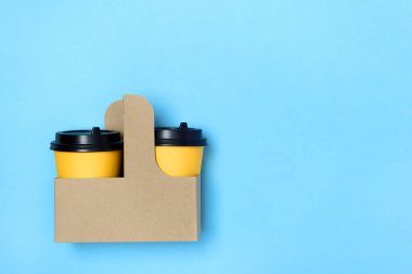 El sanatları bardağında sarı kağıt bardaklar ve açık mavi arka plan. Flatlay. Kahve konsept olsun. Sola mesaj için yer aç. Uzayı kopyala Minimalizm. maketleme.