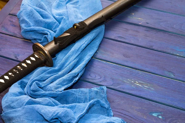 japan katana sword on the wood background with the blue shawl