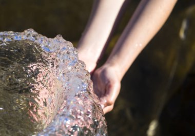 Çocuk çeşmeden su altında ellerini tutar 