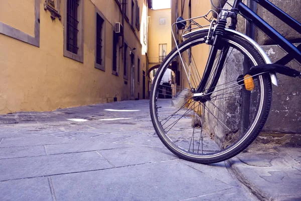 Rueda de la bicicleta negra que aparca cerca de la pared en la ciudad — Foto de Stock