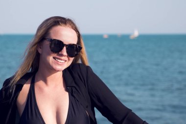 mavi deniz kenarında plajda güneş gözlüklü siyah gömlekli çekici sarışın kız