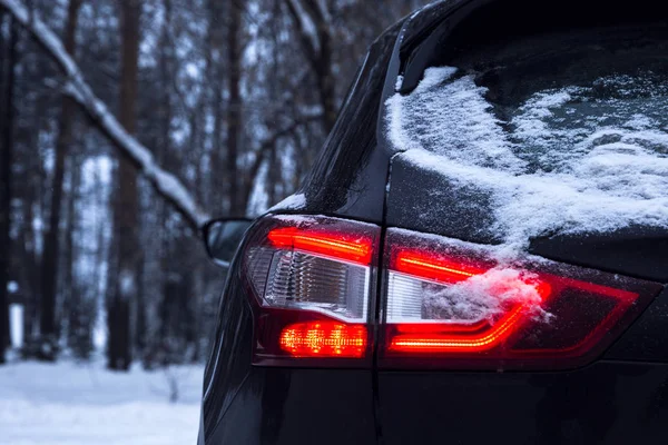 雪の明るい赤ヘッドライト カバー寒い冬の森で車 — ストック写真