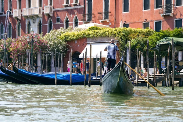 Cserzett gondolier egy klasszikus kalap és napszemüveg egy gondola, gyönyörű velencei építészeti fut a háttérben 2017-08-23-Velence, Olaszország — Stock Fotó