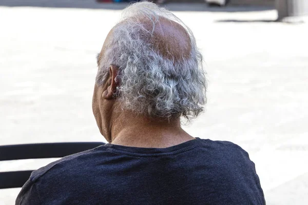 El viejo está sentado en la calle en una silla — Foto de Stock