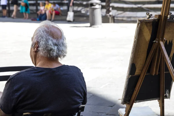 El viejo artista se sienta en la calle cerca del caballete — Foto de Stock