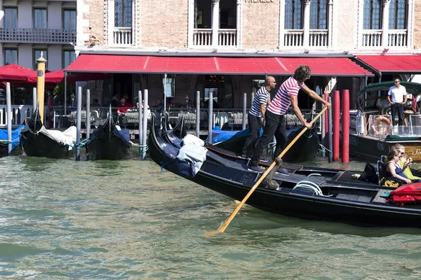 Gondoleiros bronzeados executam uma gôndola, bela arquitetura veneziana em segundo plano 2017-08-22 Venice, Italy — Fotografia de Stock