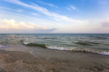 Deniz kıyısında akşam inişli çıkışlı dalgalar, bulutlar ve gökyüzü bir güçlü deniz rüzgar tarafından dağılmış