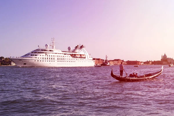 Gôndola com passageiros perto do navio de cruzeiro em Veneza, Itália ao pôr do sol (tonificado ) — Fotografia de Stock