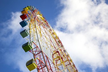 büyük modern renkli parlak dönme dolap Lunaparktaki mavi gökyüzü arka plan üzerinde