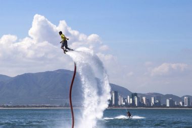 adam bir flyboard sahilde deniz mavi gökyüzü, şehir ve dağ ile arka planda Vietnam, Nha Trang 2018-01-08 biniyor 