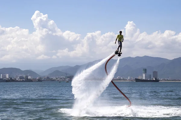 adam bir flyboard sahilde deniz mavi gökyüzü, şehir ve dağ ile arka planda Vietnam, Nha Trang 2018-01-08 biniyor 