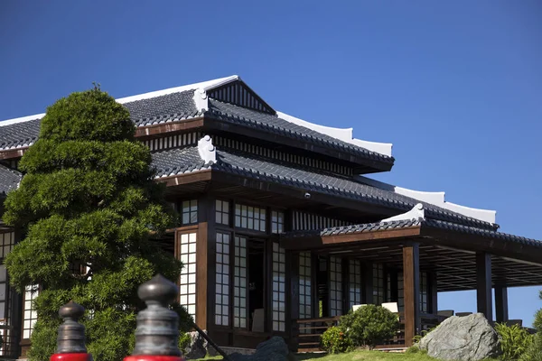 Όμορφο κτίριο στο παραδοσιακό ιαπωνικό στυλ σε έναν ιαπωνικό κήπο με πολλά πράσινα φυτά γύρω από — Φωτογραφία Αρχείου