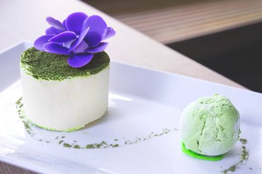 Enfes, lezzetli hafif ve yumuşak tatlı yeşil çay, çikolata çiçek ve beyaz bir plaka üzerinde bir dondurma topu