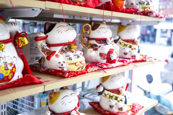 Söt traditionella leksak maskot vinkande katt ”Maneki – Neko” att föra lycka till, på hyllan i butiken (Vietnam, Nha Trang City 2018-01-10 — Stockfoto