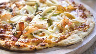 Deniz ürünleri (karides, kalamar, Yengeç, peynir ve benzeri) ahşap tahta (16:9 fotoğraf üzerinde lezzetli sıcak çıtır pizza)